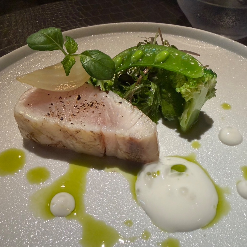 白い皿に盛り付けた肉料理と緑の野菜の一皿