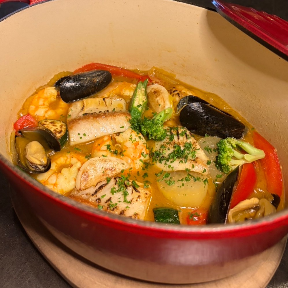 赤い鍋に盛り付けた魚介の煮込み料理